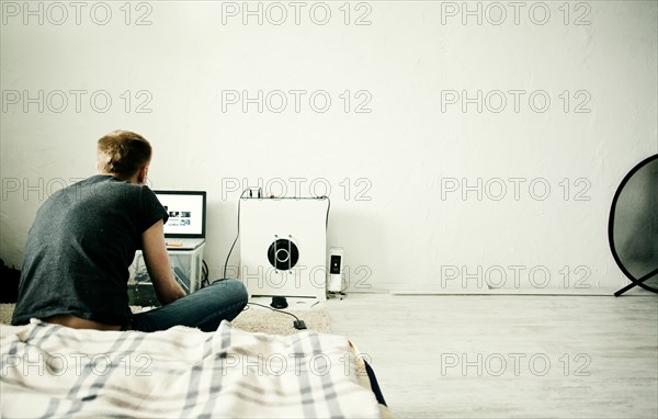 Caucasian man using laptop in bedroom