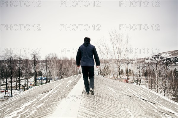 Caucasian man walking on snowy roof