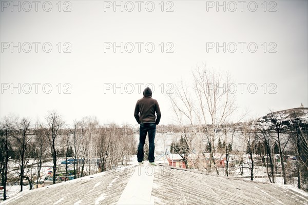 Caucasian man standing on snowy roof