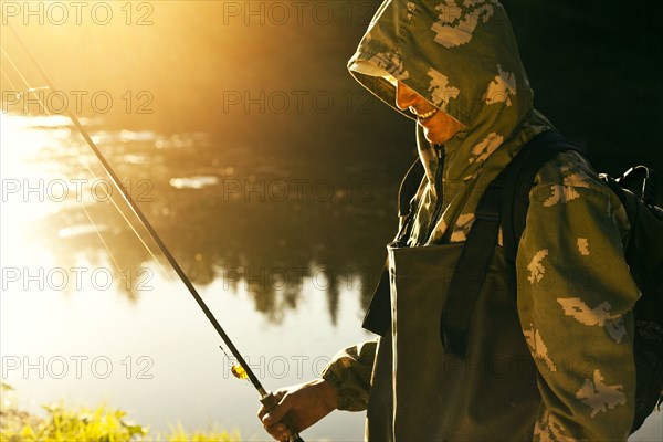 Mari man holding fishing rod at lake