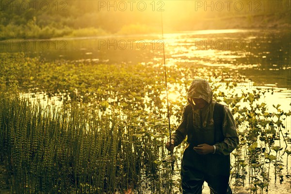 Mari fisherman carrying fishing rod at lake