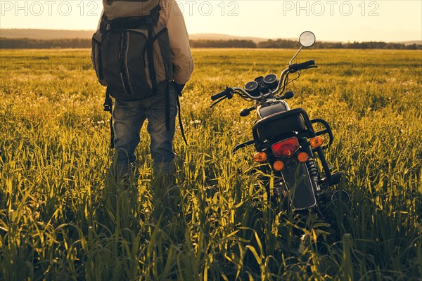 Mari man standing in field with motorcycle