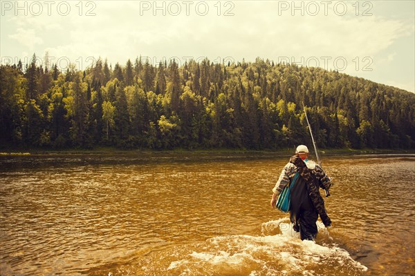 Mari fisherman carrying fishing rod in lake