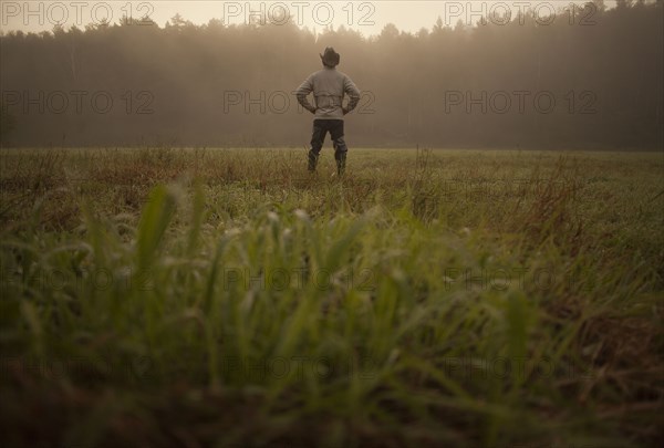 Mixed race man standing in field in rural landscape