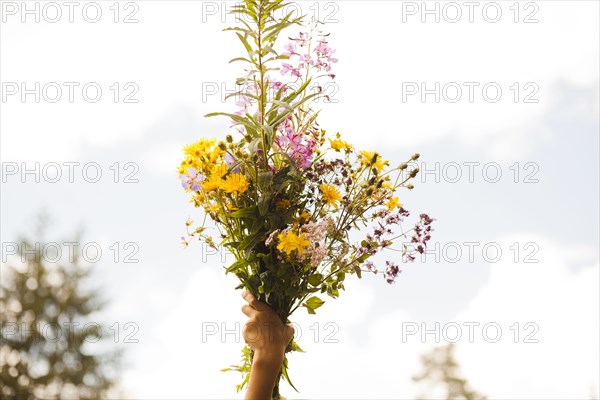 Mari boy holding up bouquet of flowers outdoors