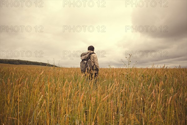 Mari man standing in tall grass in rural field