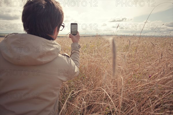 Mari man photographing rural field with cell phone