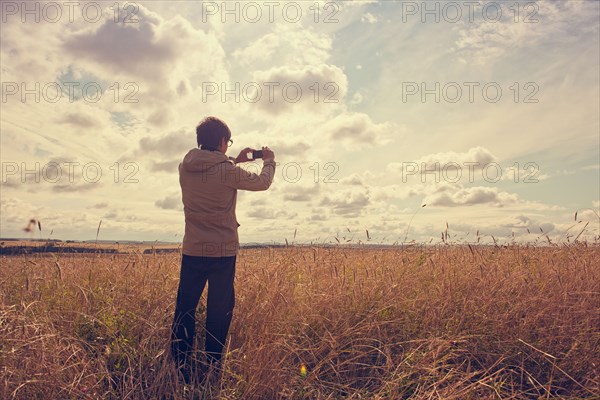 Mari man photographing rural field with cell phone