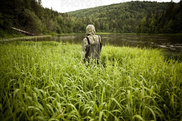 Mari man in wading boots standing in tall marsh grass