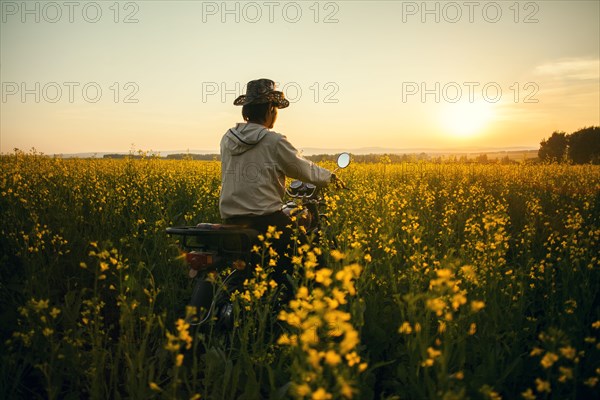 Mari man riding motorcycle in field of flowers