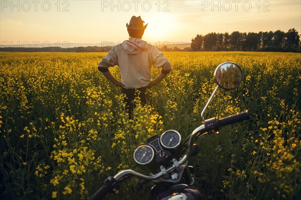 Mari man standing near motorcycle in field of flowers