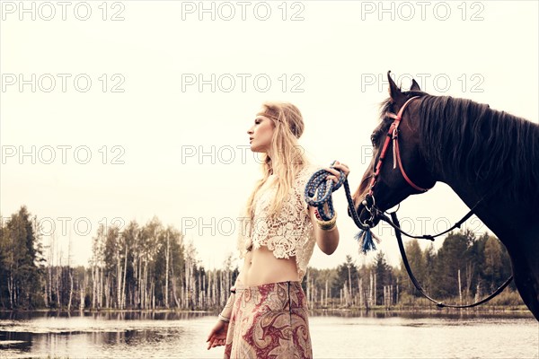 Caucasian woman leading horse near lake