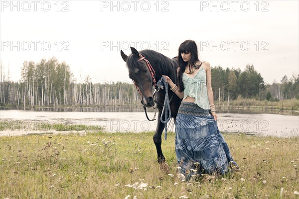 Caucasian woman leading horse near lake