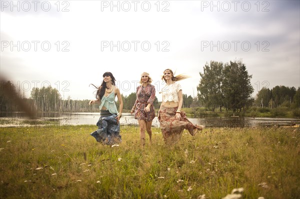 Caucasian women walking in field near lake