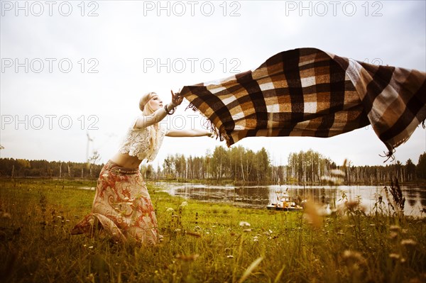 Caucasian woman spreading blanket in field