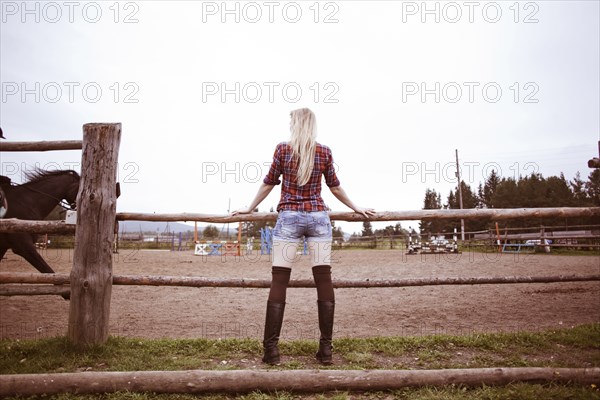 Caucasian woman watching horses on ranch