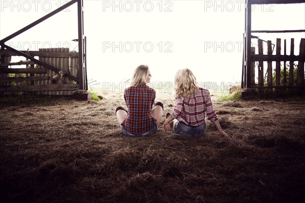 Caucasian women sitting on hay in barn