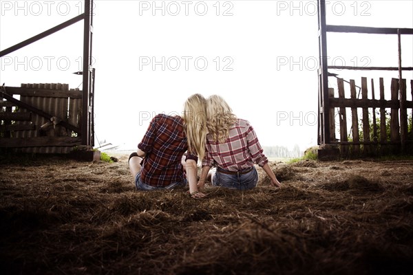 Caucasian women sitting on hay in barn