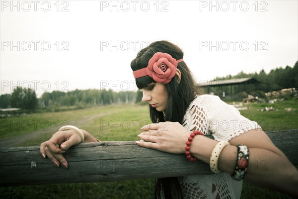 Caucasian woman leaning on wooden fence