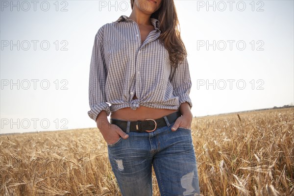 Caucasian woman standing with hands in pockets in rural field