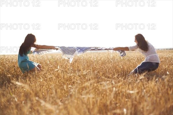 Caucasian women playing tug-of-war in rural field