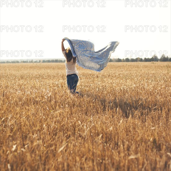 Caucasian woman carrying blanket in rural field