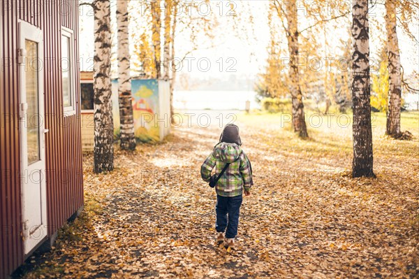 Mari boy walking in autumn leaves