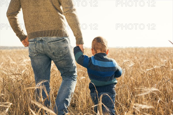 Caucasian father and son walking in rural field