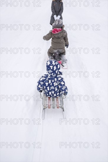 Family playing on sleds on snowy street