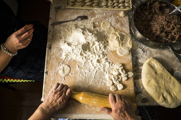 High angle view of family rolling pastry dough at kitchen table