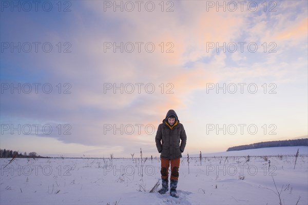 Mixed race man walking in snowy field