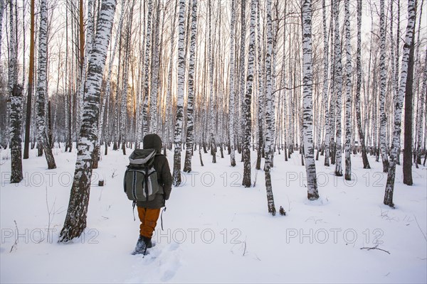 Mixed race man walking in snowy forest