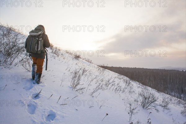 Mixed race man walking on snowy hillside