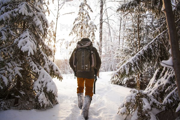 Mixed race man walking in snowy forest