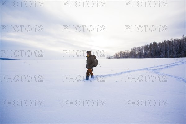 Mixed race man walking in snowy field