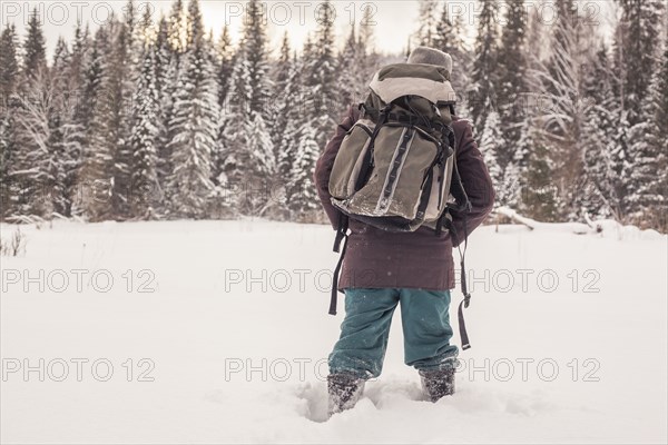 Mixed race man walking in snowy forest