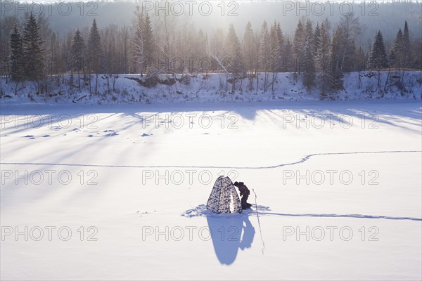 Mari man setting up tent in snowy field