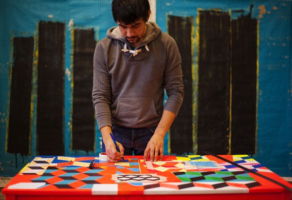 Mari man drawing on colorful table