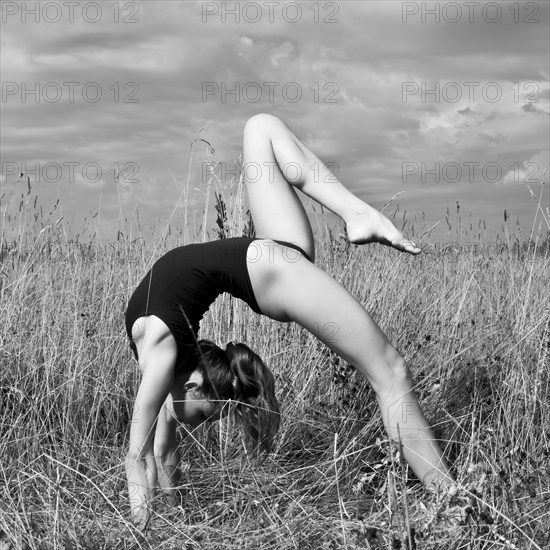 Caucasian woman doing backbend in tall grass