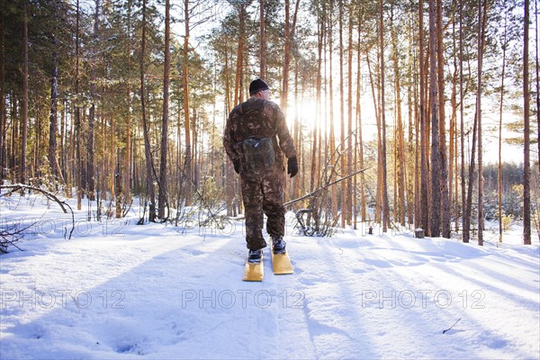 Caucasian man cross country skiing in snowy forest