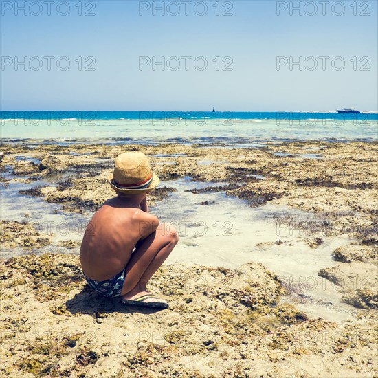 Mari boy exploring tidal pool on beach