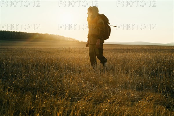 Mari man walking in rural field at sunrise