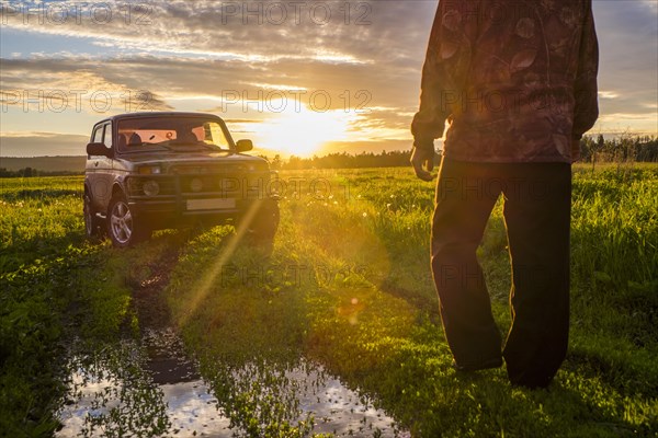 Mari man walking toward car at sunset in rural field