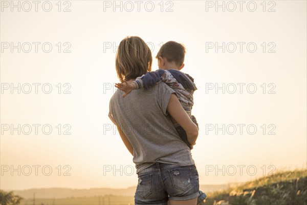 Mother holding son in rural field