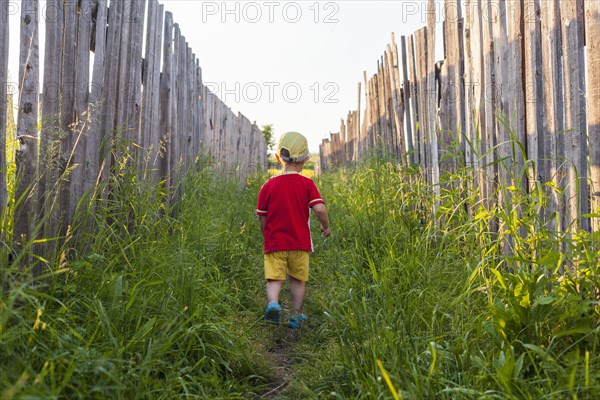 Mari boy walking in grass between fences