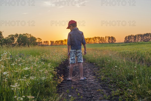 Mari boy standing in tire tracks in rural field