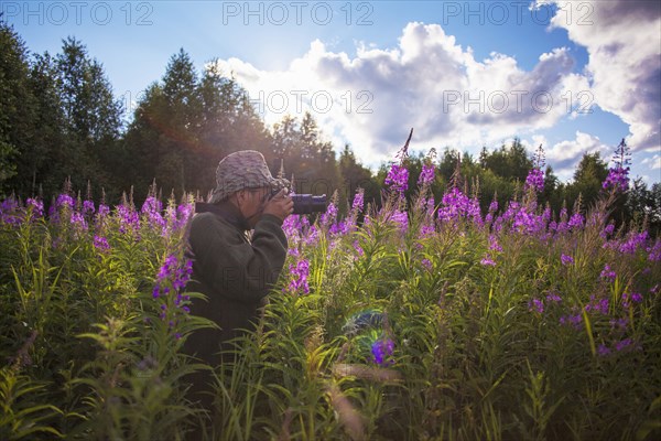 Mixed race photographer photographing flowers