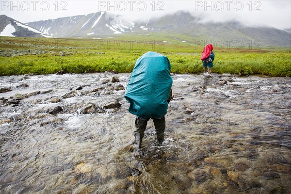 Backpackers crossing remote stream