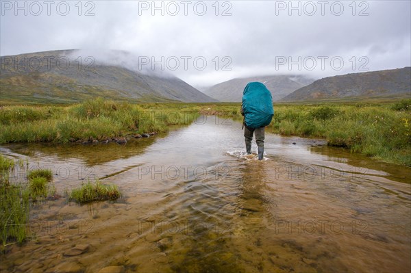 Mari backpacker walking in remote stream