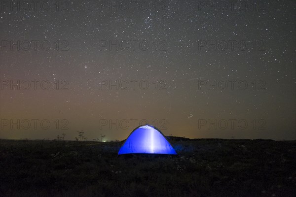 Glowing tent under starry night sky